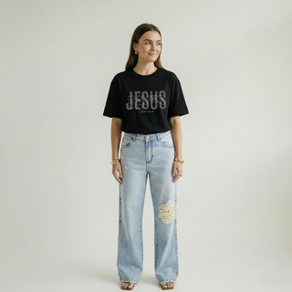Woman standing in black oversized "Jesus Saves" Luke 19:10 Christian graphic t-shirt with bold layered JESUS SAVES text, styled with light wide-leg ripped denim