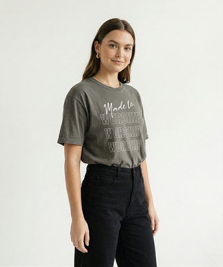 Woman smiling in medium grey "Made to Worship" oversized Christian graphic tee with bold stacked WORSHIP text, styled with high-waist black jeans