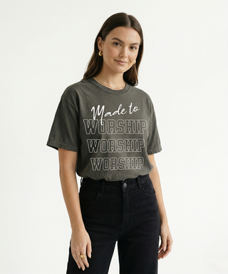 Cropped upper body view of woman in charcoal "Made to Worship" Christian graphic tee showing bold stacked WORSHIP design clearly, styled with black jeans