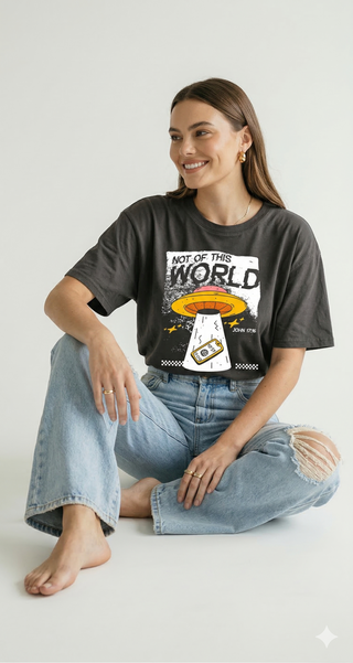 Woman sitting wearing charcoal gray "Not of This World" John 17:16 Christian UFO graphic t-shirt with ripped jeans