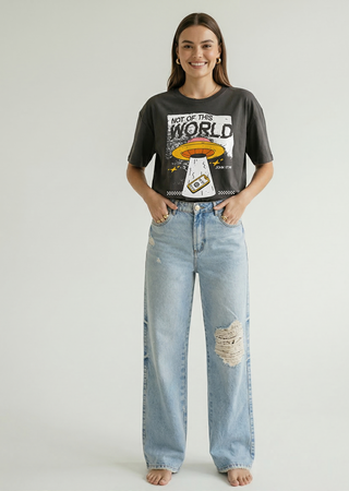 Full body front view of woman in charcoal "Not of This World" Christian UFO graphic tee with wide-leg ripped jeans, faith-inspired streetwear